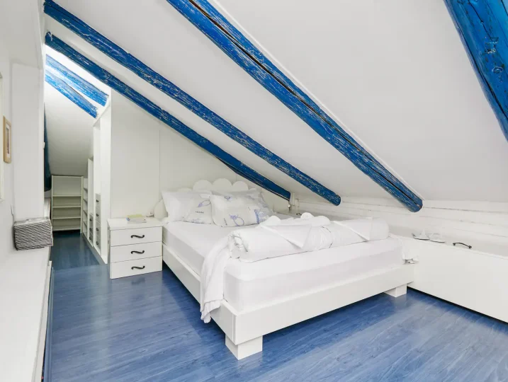 Attic bedroom with exposed blue beams at Aspida in Kotor